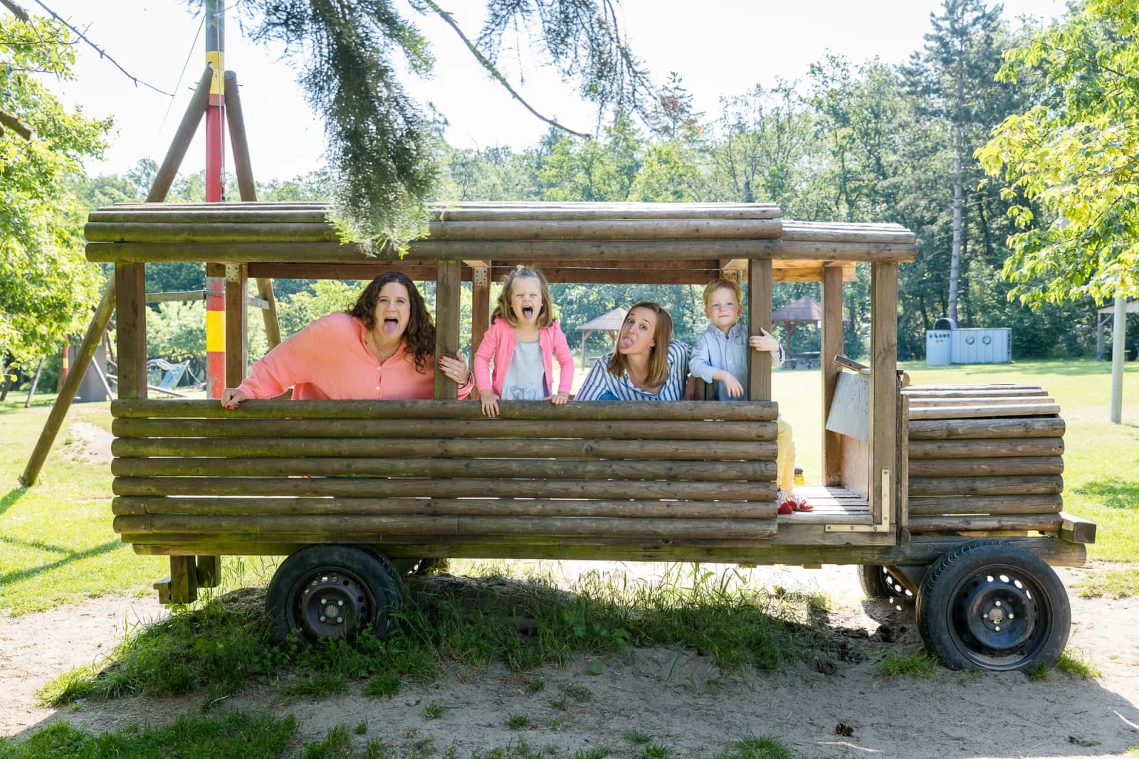 Julia und Eva mit Kindern in einem Holzbus auf dem Abenteuerspielplatz