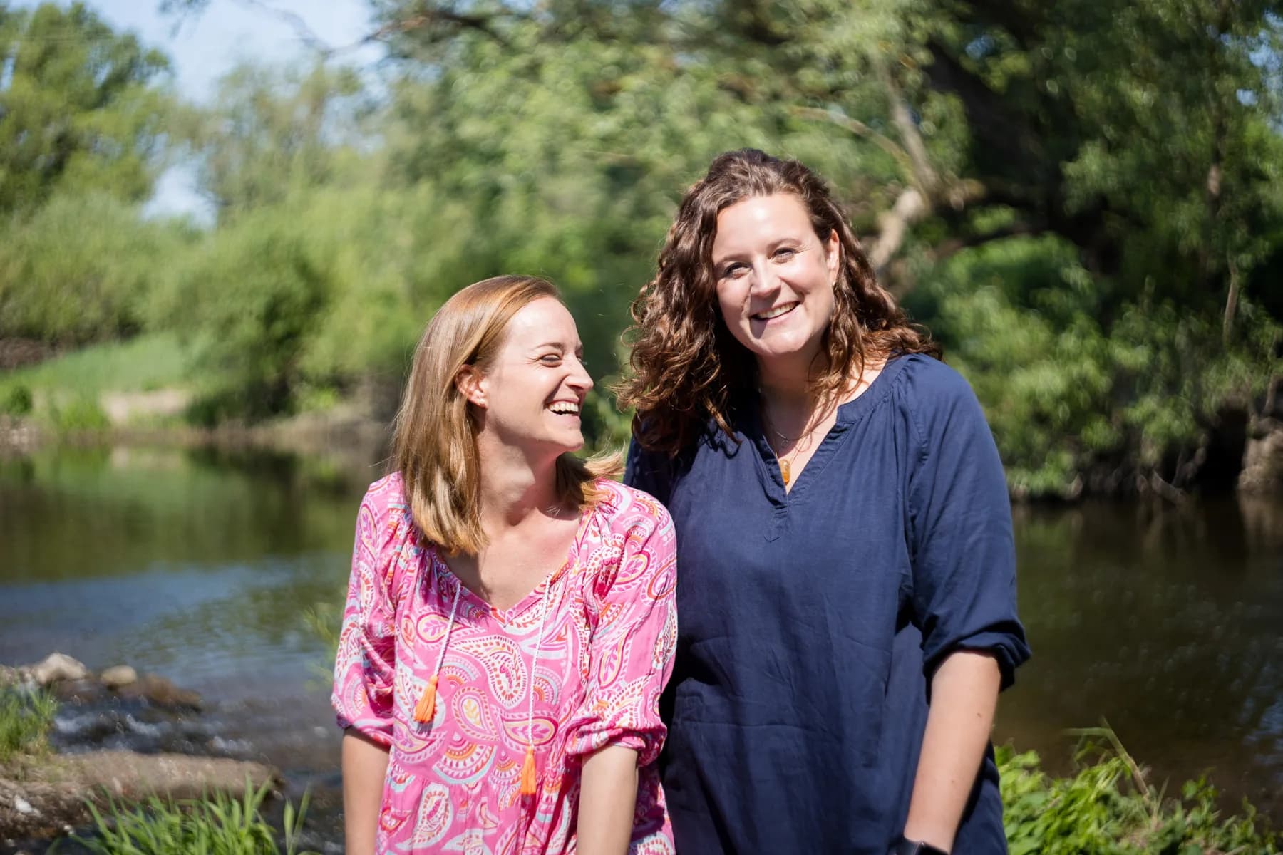 Julia Offenbacher und Eva Panzer lachend am Flussufer