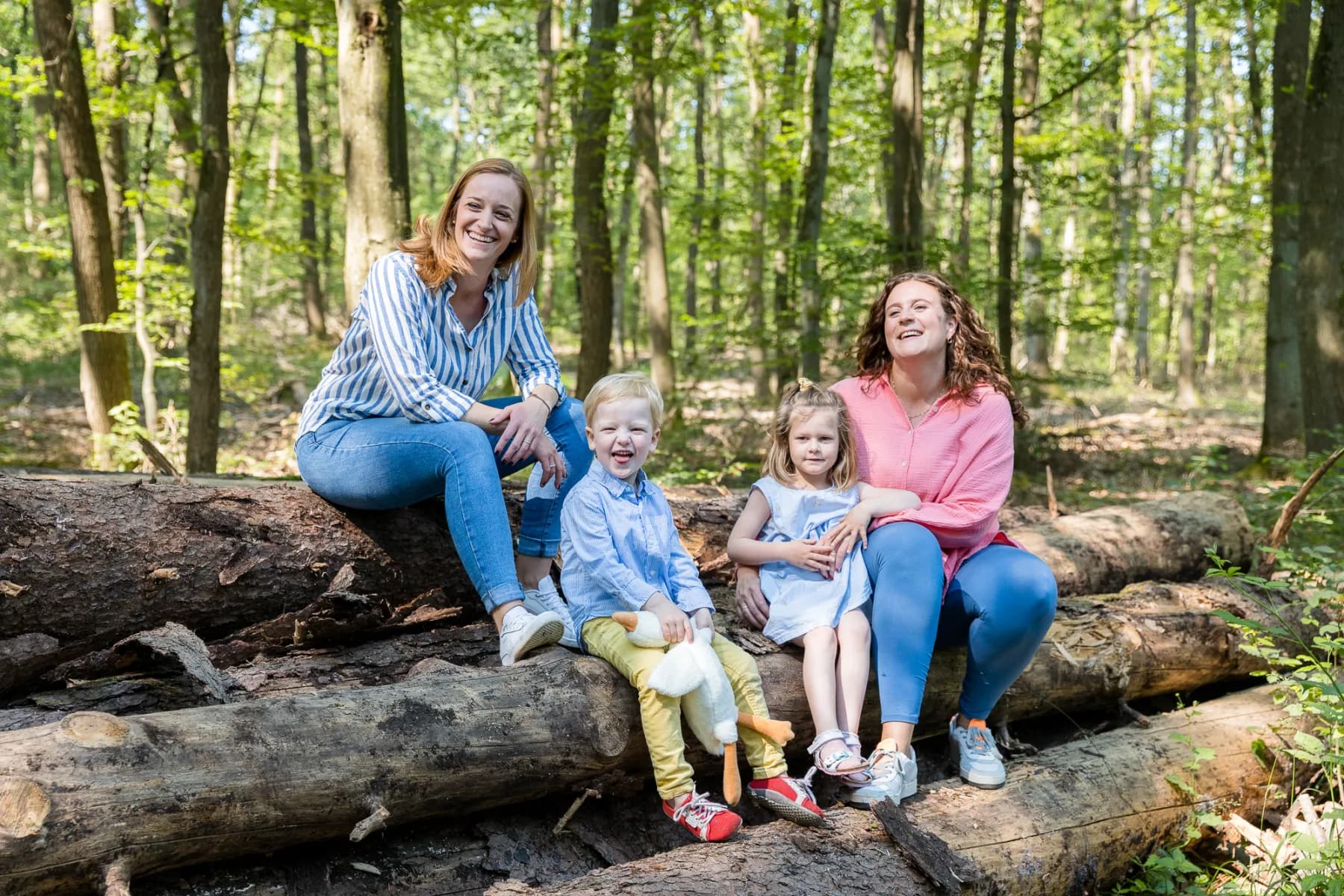 Julia und Eva mit Kindern auf Baumstämmen im Wald